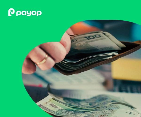 A hand opens a wallet revealing multiple 100-unit currency notes, with additional notes below. The Payop logo appears on a green background, evoking financial themes.
