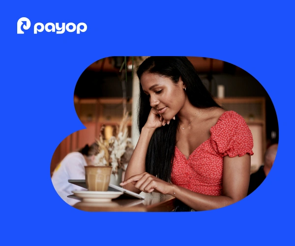 A woman in a red top smiles while using a tablet at a café, with a latte nearby. The atmosphere is relaxed and warm. Payop logo in the corner.