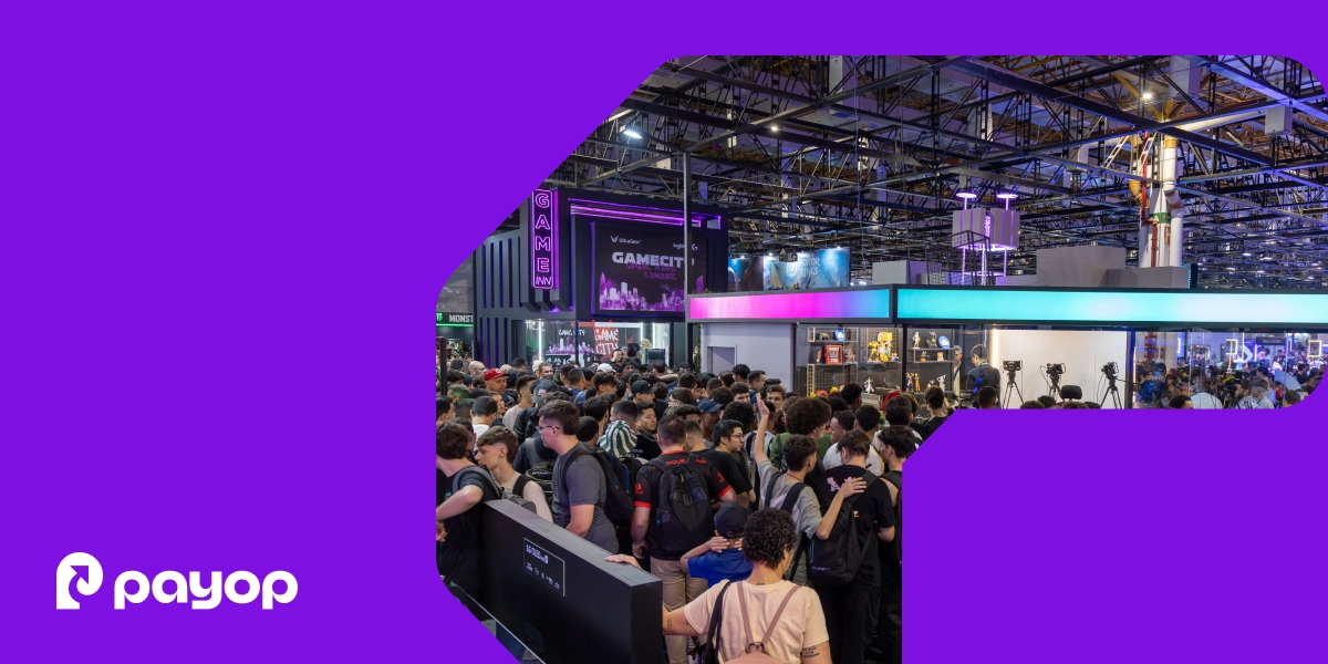 A filled exhibition hall with high ceilings, lighting trusses, and gaming booths. A large crowd of visitors fills the foreground. In the bottom-left corner, the white Payop logo. The image is framed within a graphical element on a purple background.