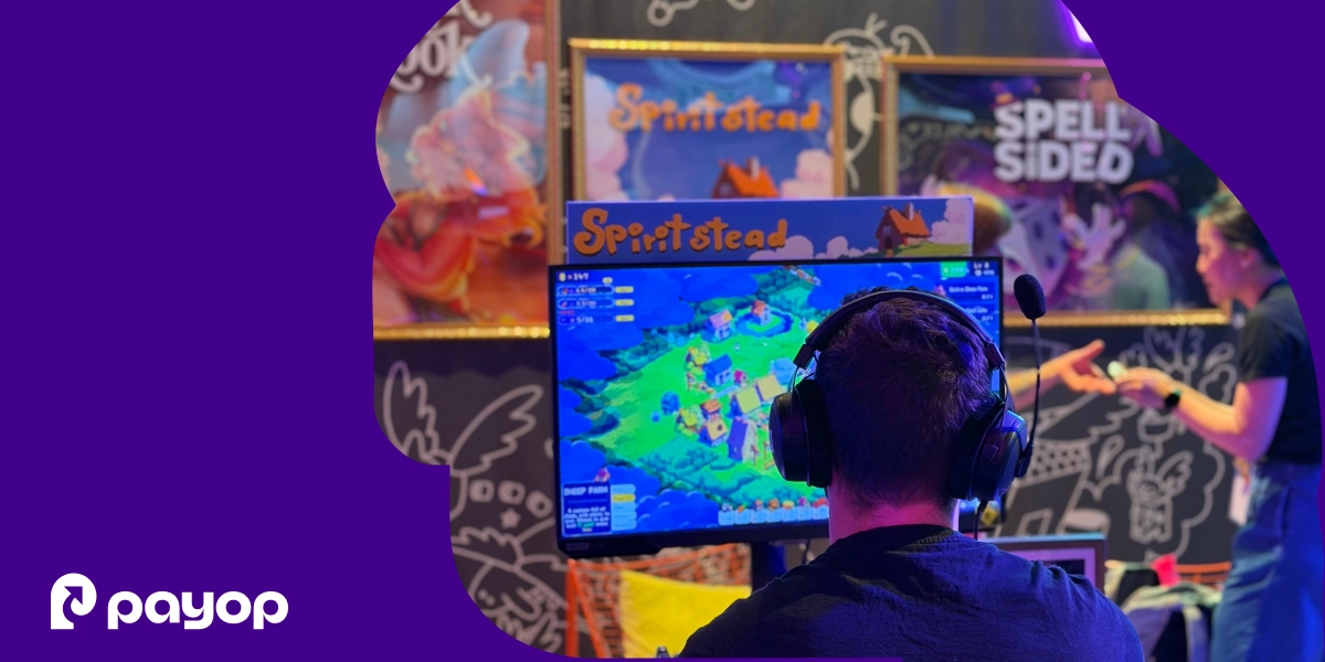 A gamer from behind, wearing headphones, looks at a computer screen showing a colorful game, within a purple frame featuring the Payop logo.