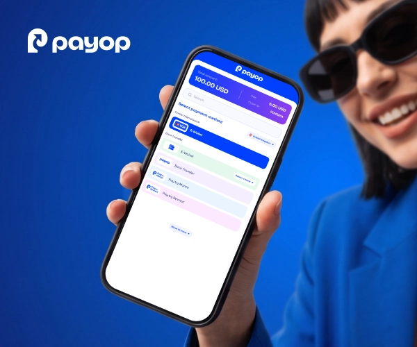 A hand holding a smartphone displaying the Payop mobile payment checkout screen with various international payment methods.