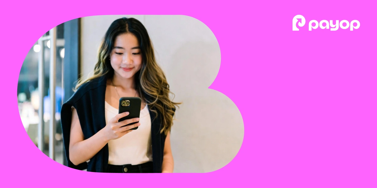 Young girl looking at a smartphone, framed by a rounded cutout on a bright pink background